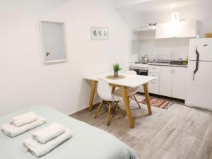 a white kitchen with a table and a white refrigerator at Tu espacio en Lomitas con cochera in Lomas de Zamora