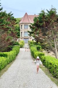 a girl walking down a gravel road in front of a house at La Sauvagère - Villa Art Deco face à Omaha Beach in Vierville-sur-Mer