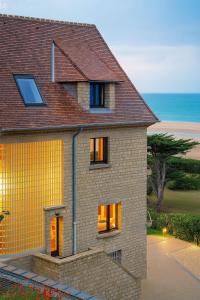 a yellow brick house with the ocean in the background at La Sauvagère - Villa Art Deco face à Omaha Beach in Vierville-sur-Mer