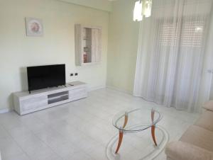 un soggiorno con TV e tavolo in vetro di Casa Vacanza SalGiò a Riposto