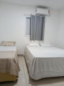 a bedroom with two beds and a window at Recanto Temporada Guarujá in Guarujá