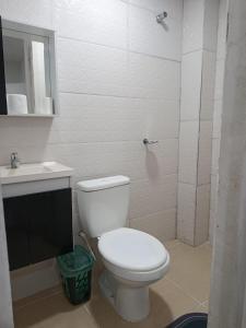 a white bathroom with a toilet and a sink at Recanto Temporada Guarujá in Guarujá