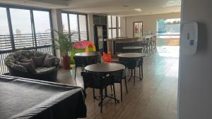 a restaurant with tables and chairs and windows at Flat em hotel de luxo em Goiânia in Goiânia