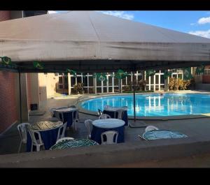 a pool with tables and chairs and a large umbrella at Transito Hotel in Araguaína