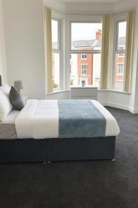 a bedroom with a large bed with two windows at CARLToN VILLAS in Wolverhampton +1 photo
