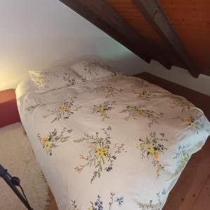 a bed with a white comforter with flowers on it at Villa Aroleid in Port-Valais