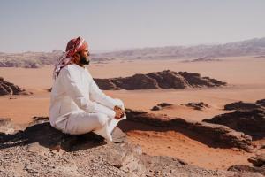 a man sitting on a rock in the desert at Wadirum Zeid Classic camp in Wadi Rum
