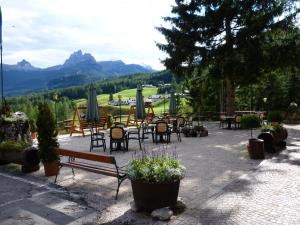un patio con mesas y sillas con montañas en el fondo en Nord Hotel, en Cortina dʼAmpezzo