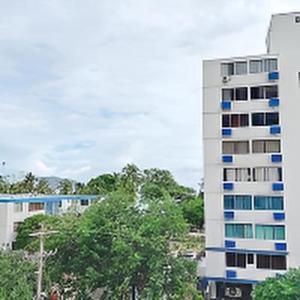 a tall white building with blue windows on it at Apartaestudio cerca al mar - Disfruta santa marta in Gaira