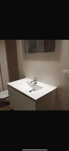 een badkamer met een witte wastafel en een spiegel bij A casa di A in Milaan +8 foto's