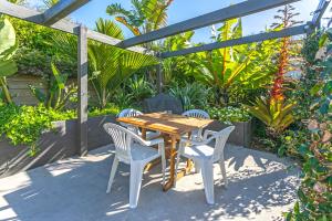 a wooden table and chairs on a patio with plants at Hahei Beach Dolphin cottage in Hahei