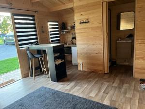 a room with a table and a kitchen with wooden walls at Le Chalet de Gaby in Vinnemerville
