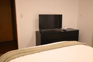 a bed with a black dresser and a flat screen tv at Bear House in Big Bear City