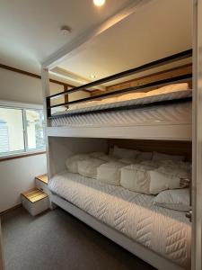 a bedroom with two bunk beds with white sheets at My Chalet Hakuba in Hakuba