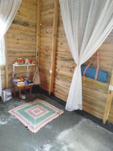 a room with a bed and a table with a curtain at Cabana e Camping da Montanha in Bocaina do Sul