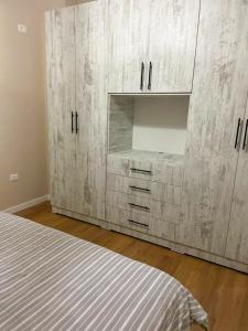 a bedroom with a bed and a large wooden cabinet at DRITA 2 Cozy Modern Apartment Fier in Fier +3 photos
