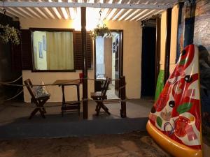 a room with a table and chairs and a surfboard at Suíte Nascer do Sol in Angra dos Reis