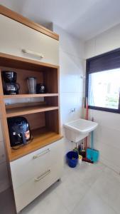 a white bathroom with a sink and a window at Conforto e praticidade em região central de Belém in Belém
