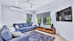 a living room with a blue couch and a tv at "Tranquillity by the Sea" your Hideaway Bay Holiday Rental-Whitsundays in Hideaway Bay
