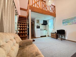 a living room with a couch and a staircase at Azumi Holiday House in Azumino