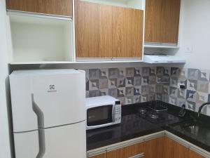 a kitchen with a white refrigerator and a microwave at Flat Av Rio Branco Centro SP in Sao Paulo