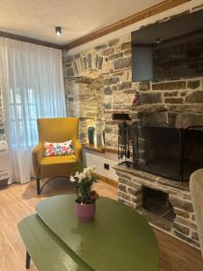 a living room with a stone fireplace and a yellow chair at Cumaku Boutique Hotel & Spa in Gjirokastër
