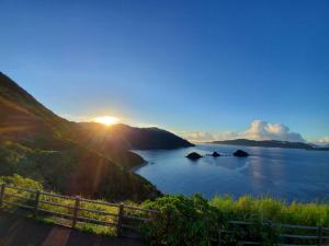 a view of a body of water with the sun setting at 西古見の宿だるま in Setouchi