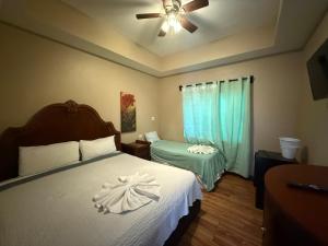 een slaapkamer met een bed en een plafondventilator bij Hotel Royal Blue & Golf Cart Rental in San Pedro