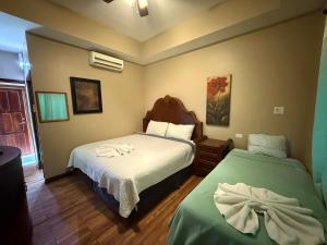 een slaapkamer met twee bedden met handdoeken erop bij Hotel Royal Blue & Golf Cart Rental in San Pedro