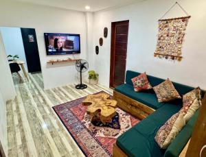 a living room with a green couch and a tv at Araw Boutique in General Luna