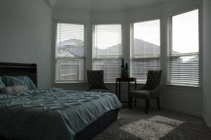 1 dormitorio con 1 cama, 2 sillas y ventanas en Amazing Katy home, en Katy