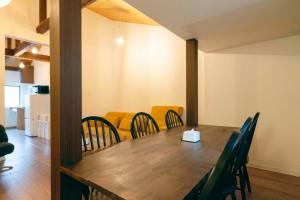 a dining room with a wooden table and chairs at TasoneUrbanStayOsaka 梅田中津1 in Osaka