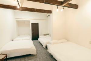 three beds in a room with white walls at TasoneUrbanStayOsaka 梅田中津1 in Osaka