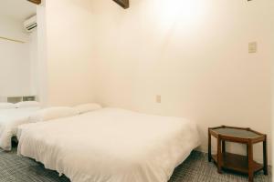 two beds in a white room with a table at TasoneUrbanStayOsaka 梅田中津1 in Osaka +21 photos