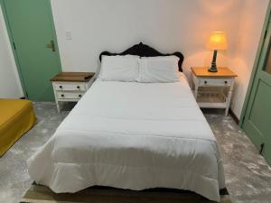 a bedroom with a large white bed and two night stands at Suite IPÊ ROSA in Areal
