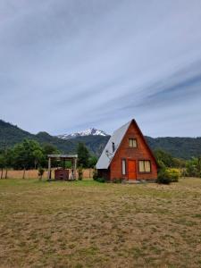 un granero en un campo con montañas en el fondo en Cabaña en Choshuenco con Tinaja, en Choshuenco