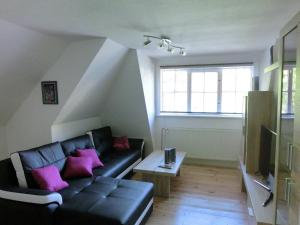 a living room with a black leather couch and pink pillows at Alpine Escape in Wildemann in Wildemann