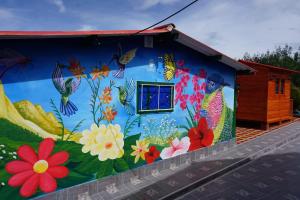 a mural on the side of a house with flowers at Camping el triunfo in Montecillo