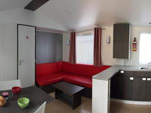 a living room with a red couch in a kitchen at Mobil home confortable avec terrasse pour 6 personnes - API-1-52-304 in Brétignolles-sur-Mer