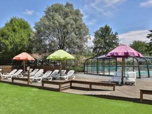 a group of chairs and umbrellas on a patio at Mobil-home confortable avec terrasse, 3 chambres, 6 couchages - API-1-52-492 in La Mothe-Achard