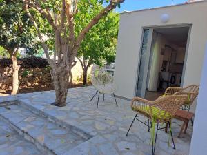 a patio with chairs and a tree next to a building at Dea's Garden home in Himare