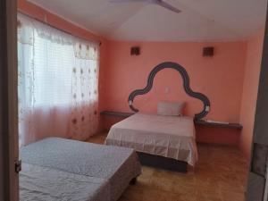 クユトランにあるBungalows los trébolesのオレンジ色の壁の部屋にベッドが2つある