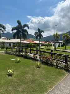 a fence with flowers and palm trees in a park at Village Ducado in Mangaratiba