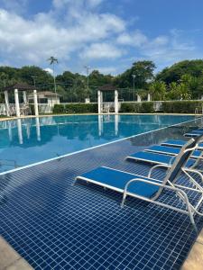 a row of lounge chairs in a swimming pool at Village Ducado in Mangaratiba