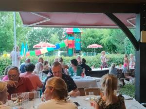 un groupe de personnes assises à des tables dans un restaurant dans l'établissement Chalet 6 pers avec Terrasse - Cuisine équipée - API-1-52-539, à Dévillac