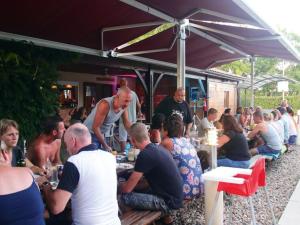 Un groupe de personnes assis à table sous un parapluie dans l'établissement Chalet 6 pers avec Terrasse - Cuisine équipée - API-1-52-539, à Dévillac