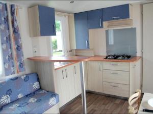 a small kitchen with blue cabinets and a counter at Mobil-home confortable avec terrasse - API-1-52-524 in Brétignolles-sur-Mer