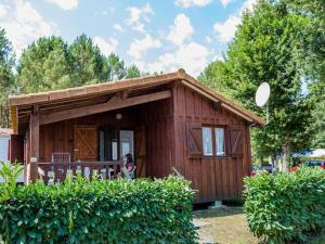 a small house with a woman standing outside of it at Chalet 6 personnes avec terrasse à Sainte-Eulalie-en-Born - API-1-52-708 in Sainte-Eulalie-en-Born +8 photos