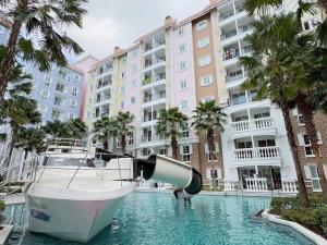 un bateau dans l'eau devant un bâtiment dans l'établissement Blue lagoon seven sea jomtien, à Na Jomtien