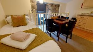 a room with two beds and a table and a kitchen at Dolgun Uchaf Historic B&B and Cottages with Boutique Bedrooms In The Heart of Snowdonia in Dolgellau